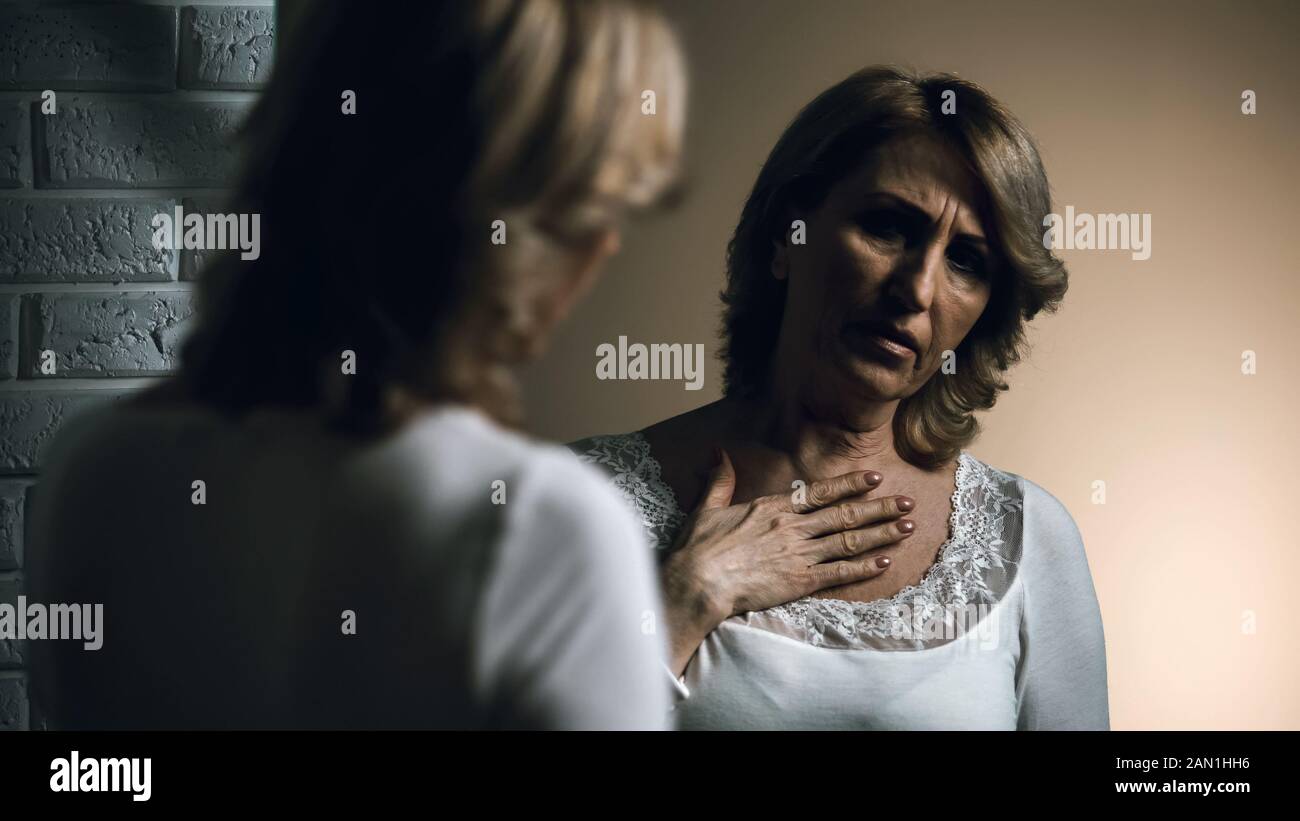 Depressive Seniorin betrachtet Reflexion im Spiegel, Hautkrebs, Sorgen Stockfoto