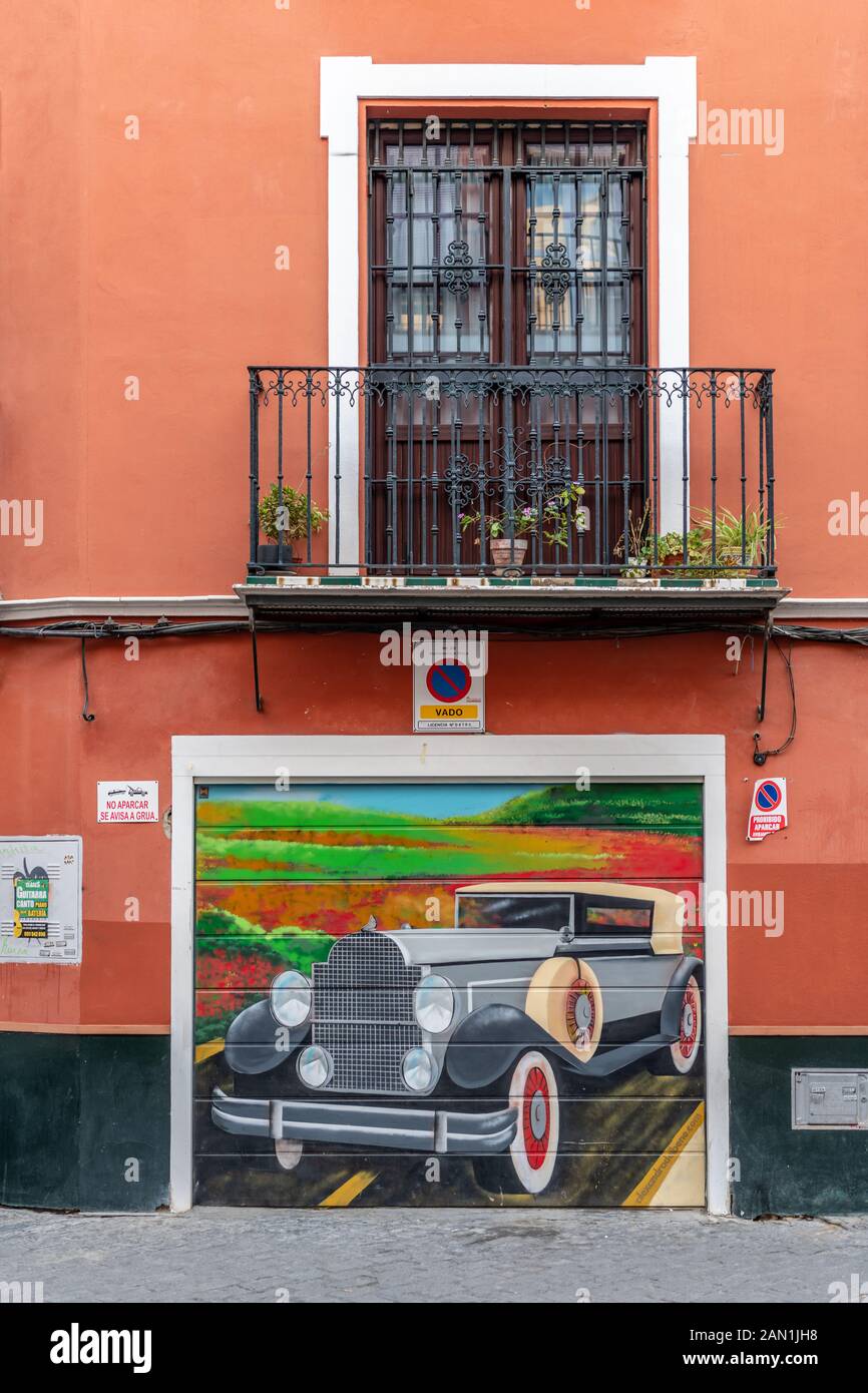 Ein buntes Bild von einem Oldtimer auf der Tür von einer Garage in Sevilla Stockfoto