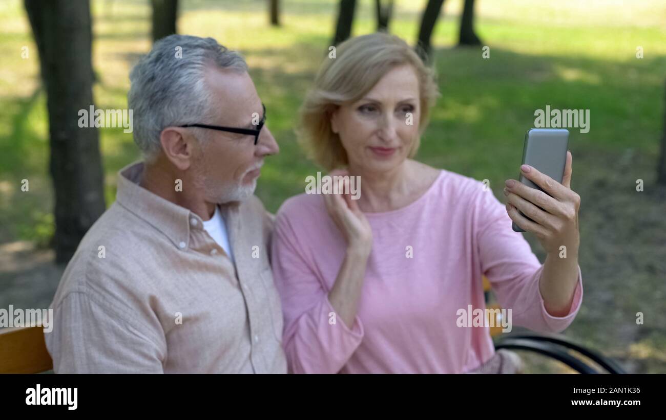 Schöne ältere Frau im Smartphone kamera Reflexion suchen, wobei selfie Stockfoto