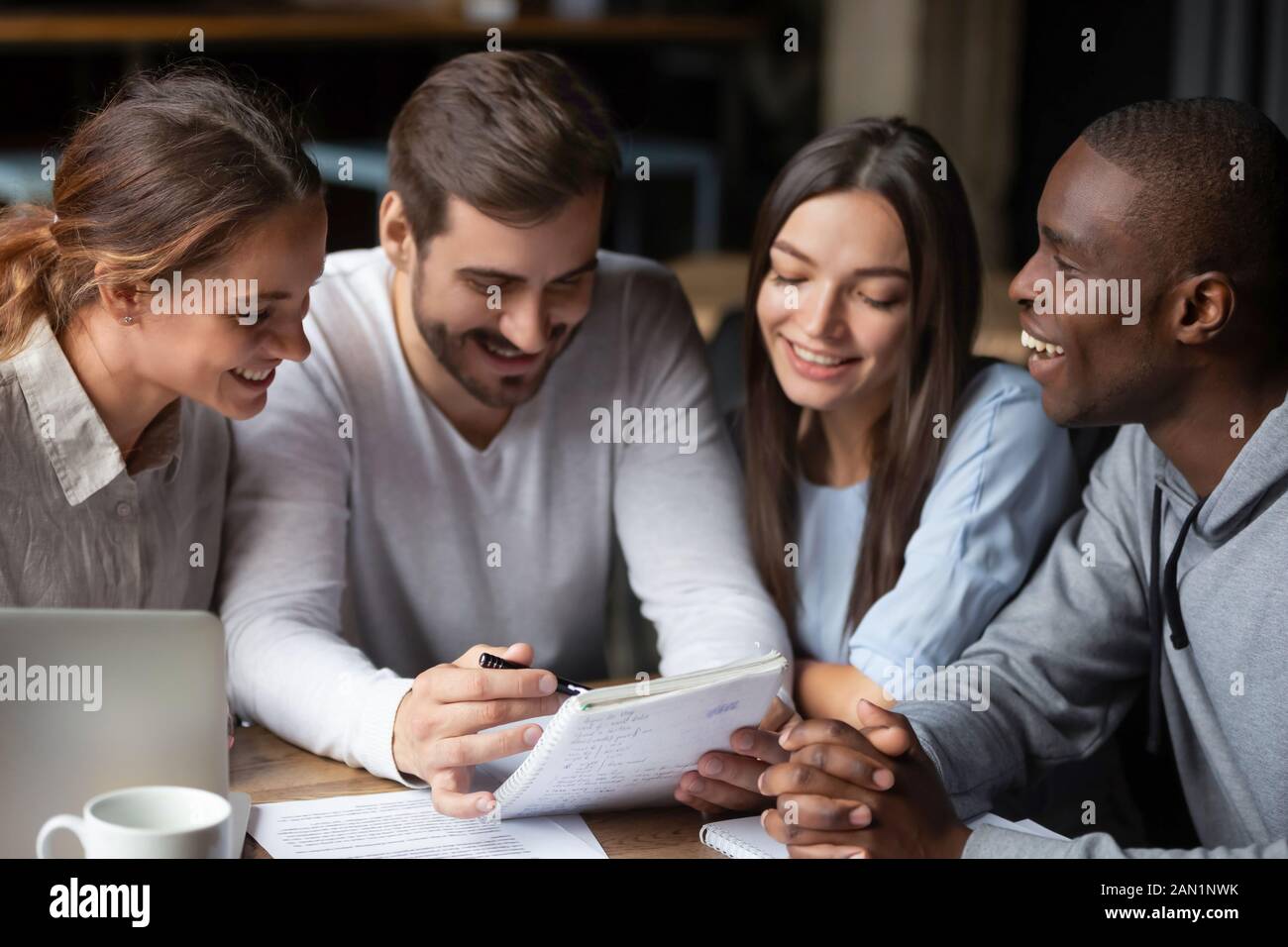 Fröhliche internationale Studenten sammeln sich im Café, das zusammen studiert Stockfoto