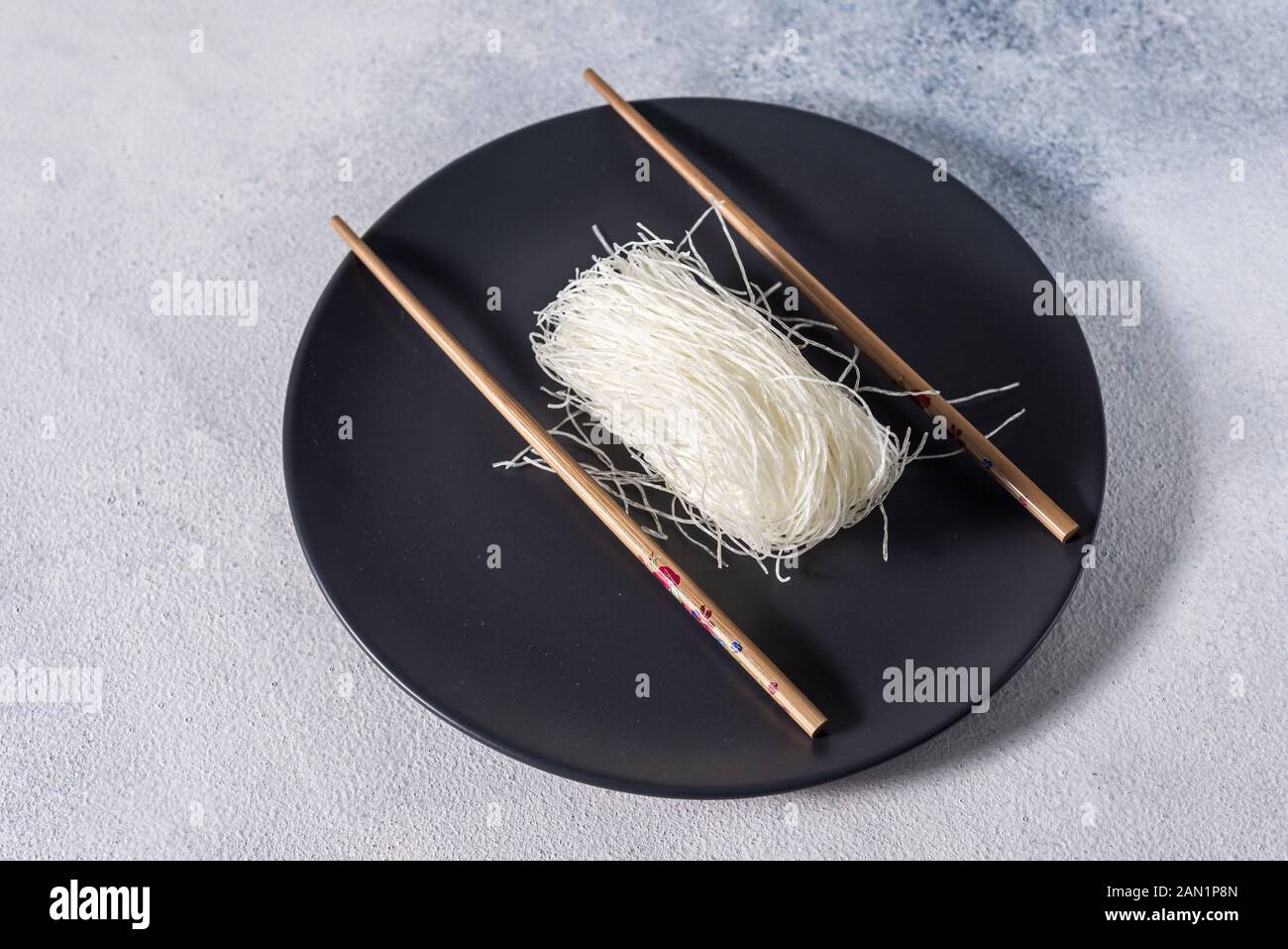 Chinesische Glasnudeln mit Stäbchen auf einem dunklen Platte mit Platz für Text Stockfoto