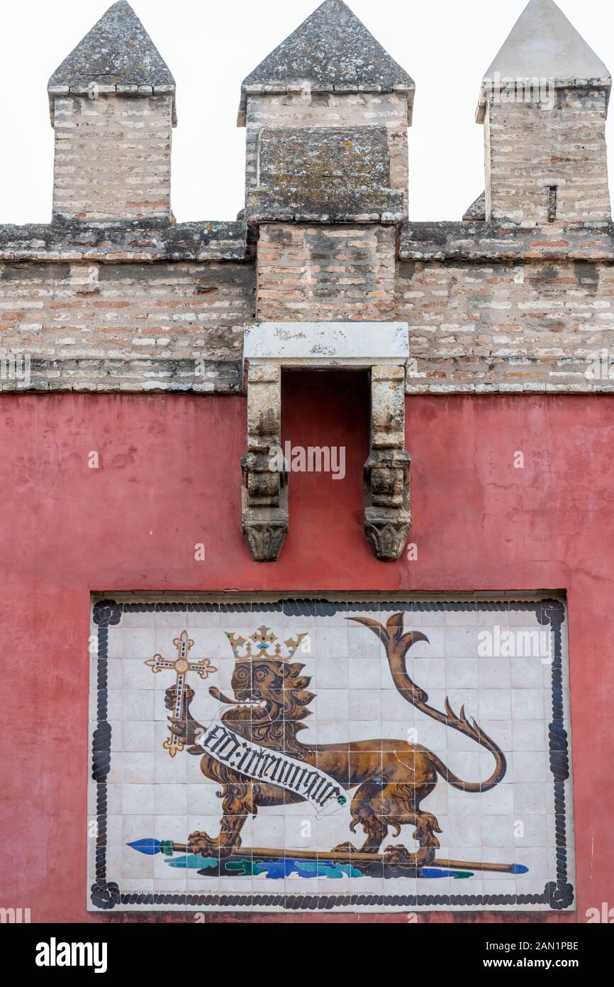 Ein bekrönter Löwe, der ein Kreuz und ein Banner mit gotischer Schrift Ad: Utrumque trägt, sitzt über der Puerta del Leon im Echten Alcázar von Sevilla Stockfoto