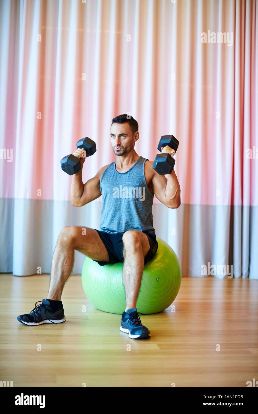 Ein Mann, der in der Turnhalle Schulterpressen macht. Stockfoto