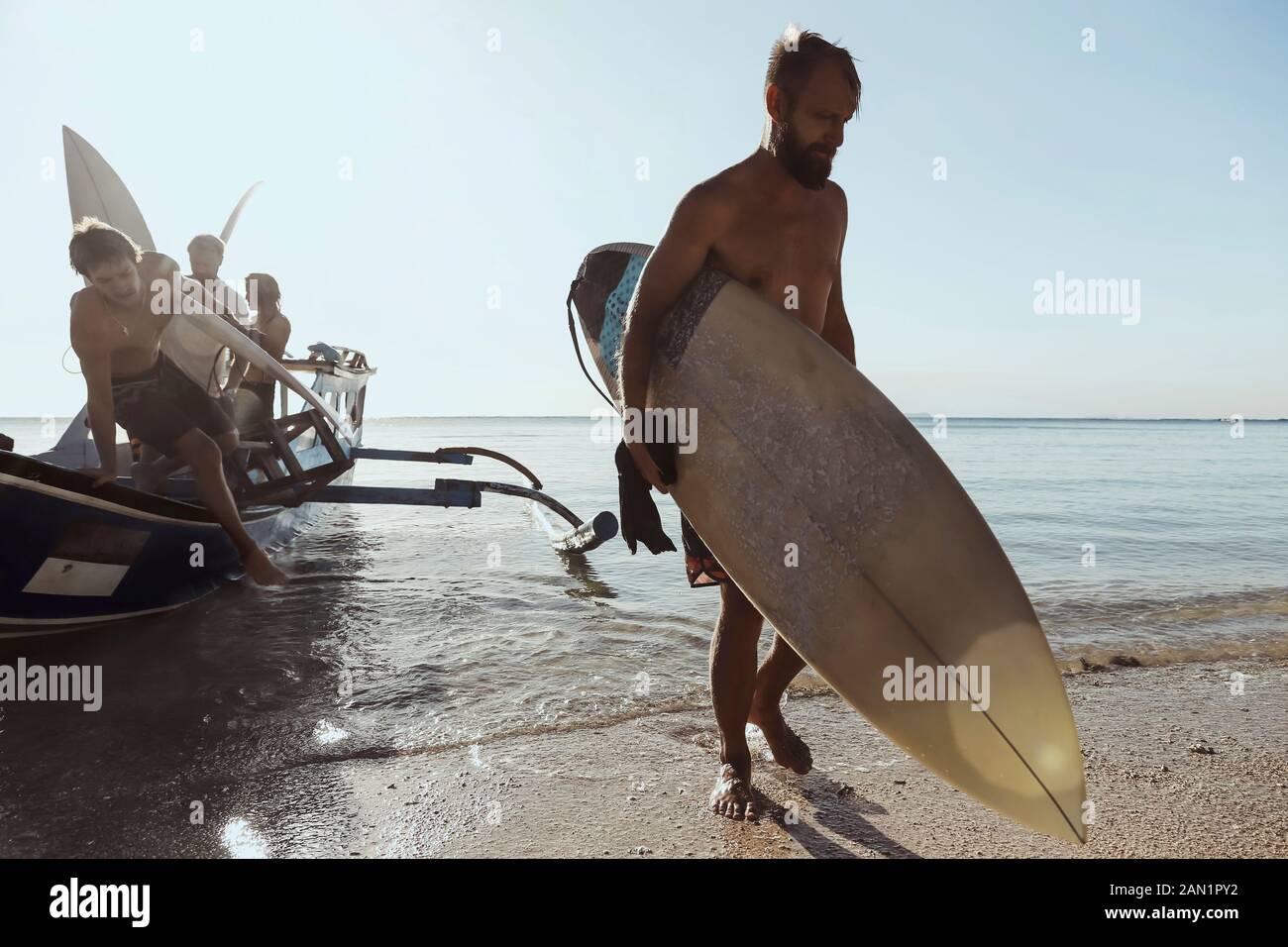 Erwachsene Männer tragen Surfbretter beim Entladen des Schiffes Stockfoto