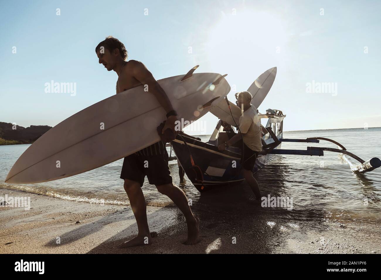 Erwachsene Männer tragen Surfbretter beim Entladen des Schiffes Stockfoto
