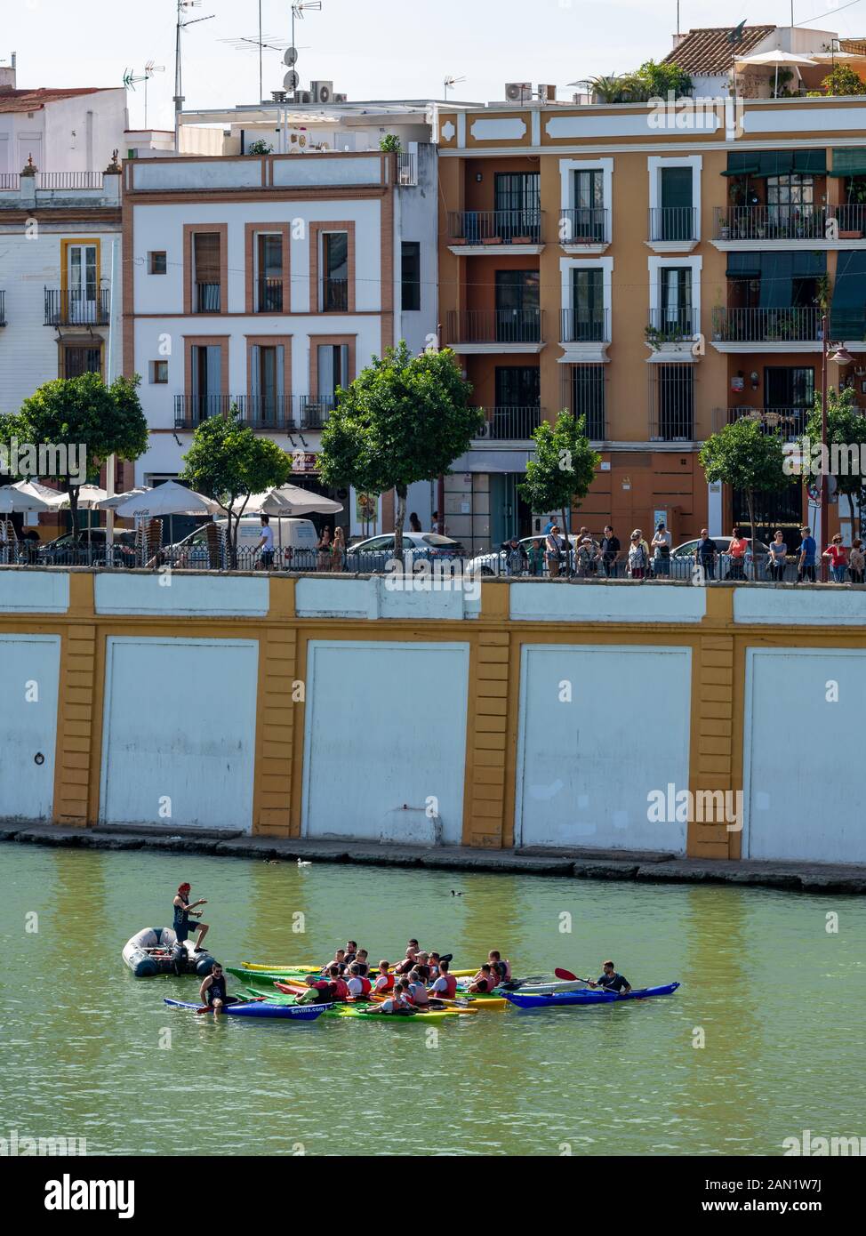 Kajakfahrer treffen sich auf einer Kayak-Sevilla-Tour zu einem Briefing mit ihrem Reiseleiter auf dem Fluss Guadalquivir an der Brücke Puente de Isabel II. Stockfoto