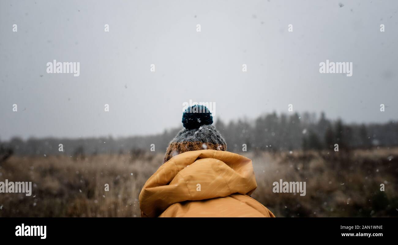 Die Rückseite eines Bommel Hut auf einem Kind spielen draußen im Schnee Stockfoto