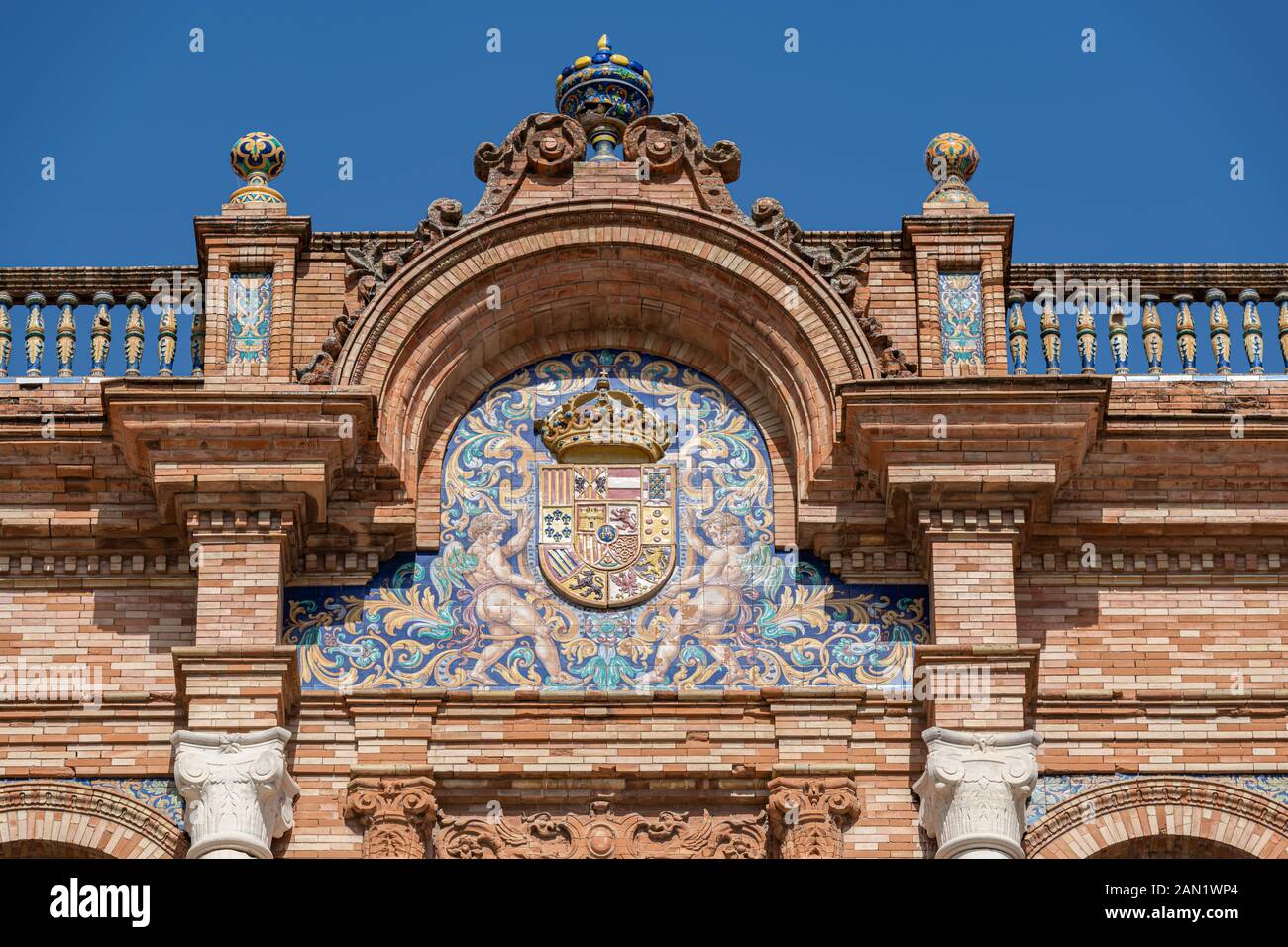 Der zentrale Bogen des Gebäudes "Plaza de España" von Aníbal González aus dem Jahr 1929 mit seinem azulejos (gekachelten) Wappen und seiner Dekoration, der Balustrade und der farbenfrohen Urne. Stockfoto