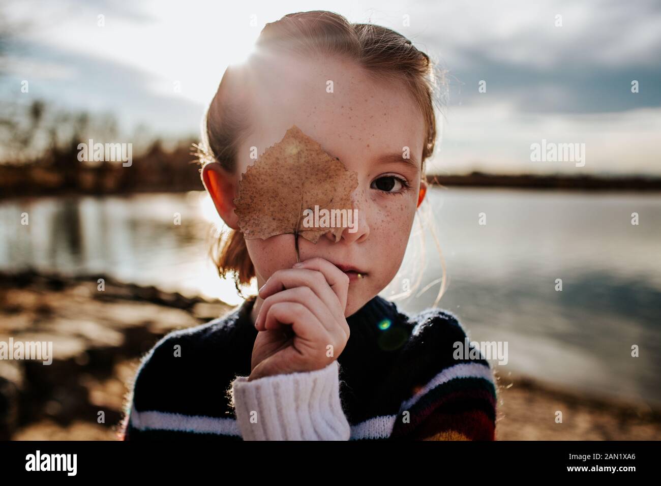 Porträt eines Mädchens mit einem Blatt, das die Hälfte ihres Gesichts bedeckt Stockfoto