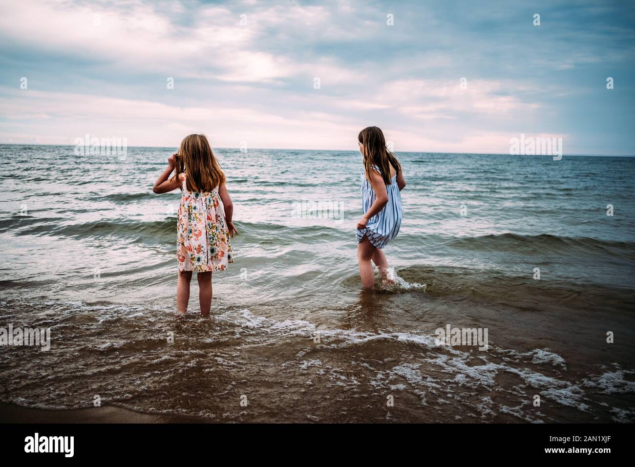 Mädchen stehen in See in ihren Kleidern suchen weg von der Kamera Stockfoto