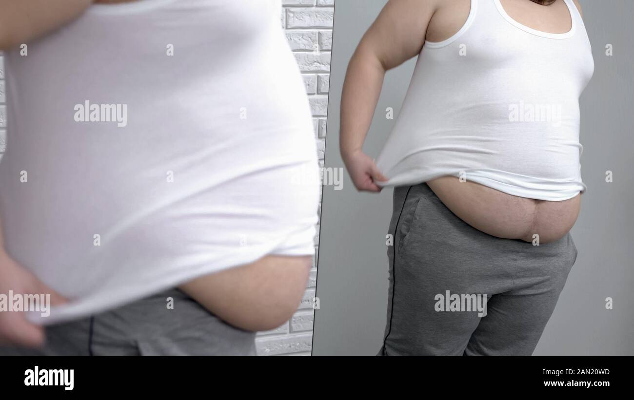 Übergewichtige Männer setzen auf weißem Hemd vor Spiegel, Wunsch, Gewicht zu verlieren Stockfoto