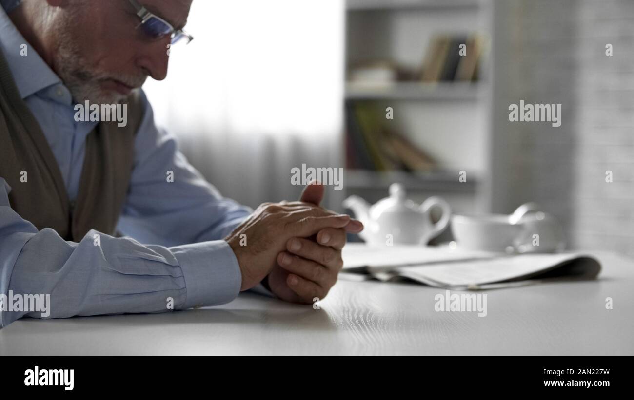 Rentner mann am Tisch saßen und auf seine Hände, deprimiert Stockfoto