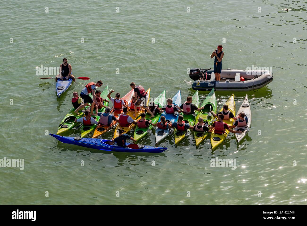 Kajakfahrer üben auf einer Kayak-Sevilla-Tour, ihr Gleichgewicht zu halten, während sie auf dem Guadalquivir River in Sevilla von Boot zu Boot fahren. Stockfoto