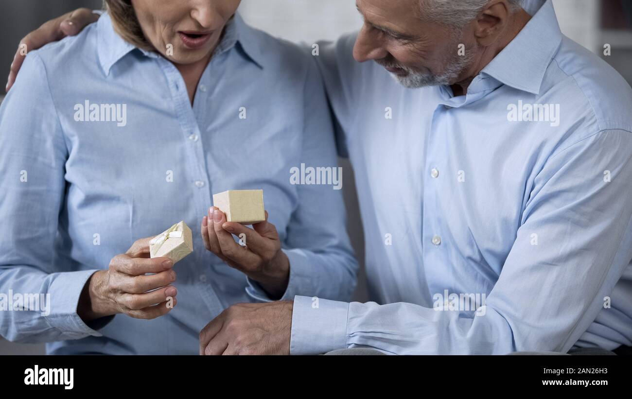 Ältere Dame mit vorhanden, liebevollen Mann sie umarmen, glückliches Paar überrascht Stockfoto
