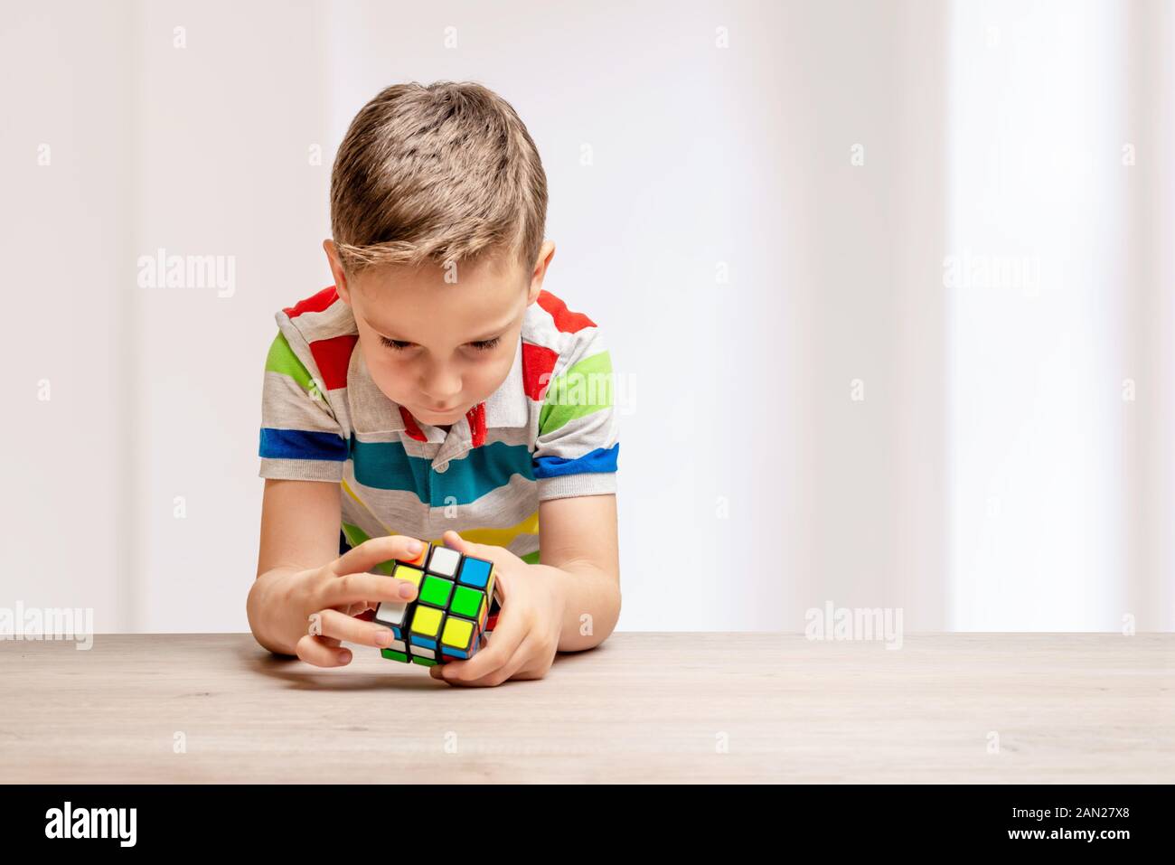 Kind löst einen Rubik's Cube. Konzept der speedcubing puzzle Wettbewerb. Kopieren Sie Platz neben Stockfoto