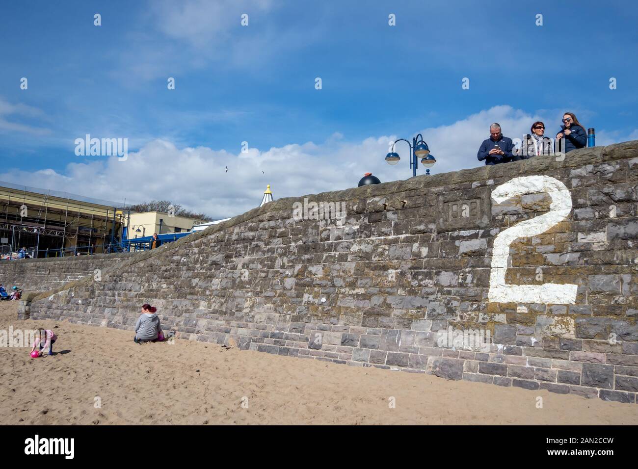 Touristen am Strand und der Strandpromenade auf Barry Island in Wales, Großbritannien. Stockfoto