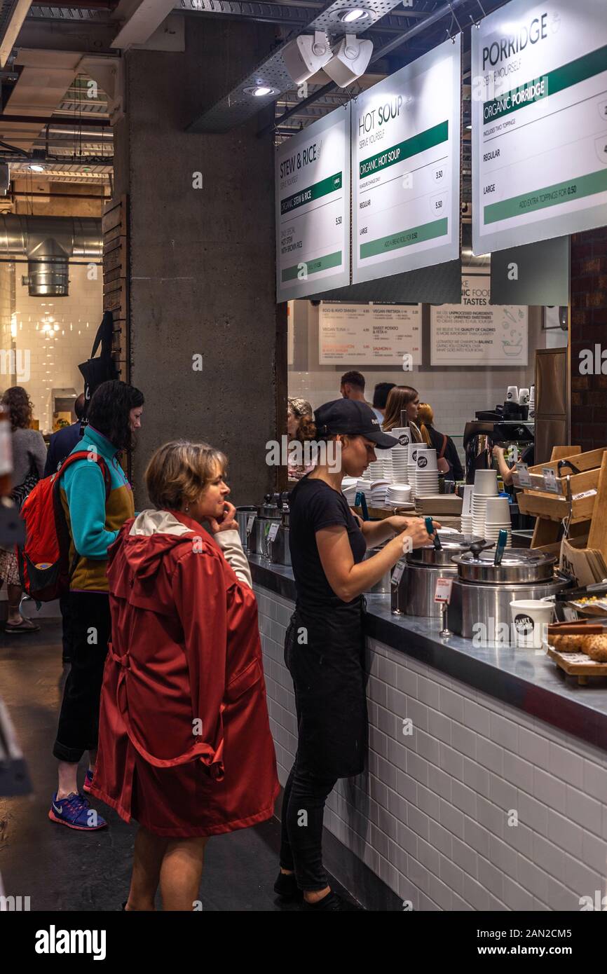 Kunden, die warten Essen im inneren Planeten Organische zu bestellen, Tottenham Court Road, London, England, UK. Stockfoto