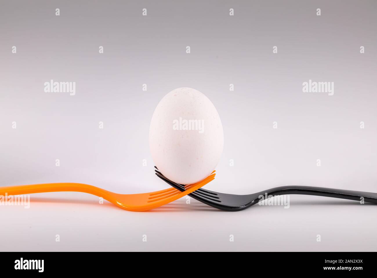 Eine schwarze und eine orange Gabel Holding ein Ei. Konzept einschließenden Teamarbeit Stockfoto