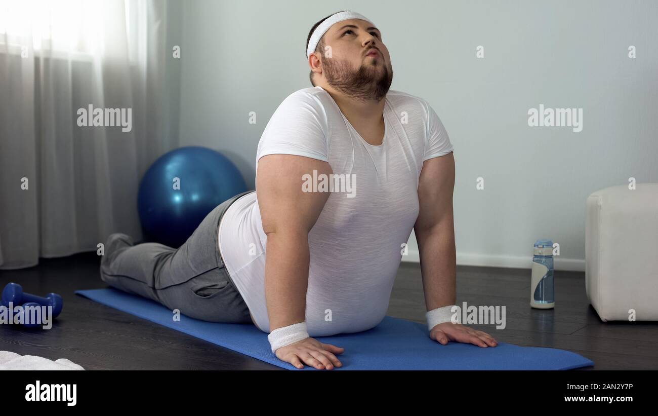 Übergewichtige Menschen, die sich zu Hause, in den nach oben schauenden Hund darstellen, flexible Wirbelsäule Übung Stockfoto