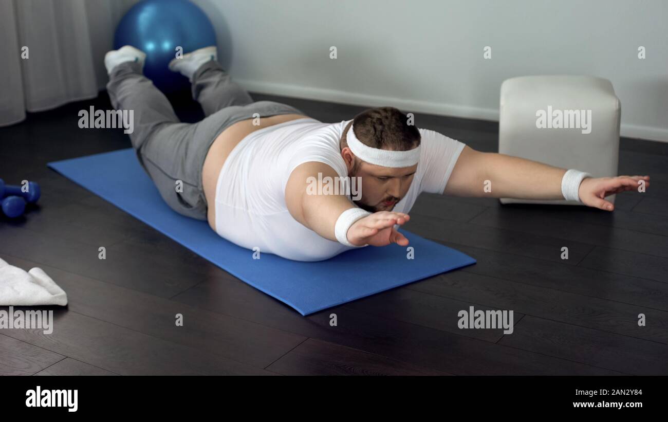 Sorgfältige mollig Mann Stärkung der Rückenmuskulatur zu Hause, statische Übung, Stromversorgung Stockfoto