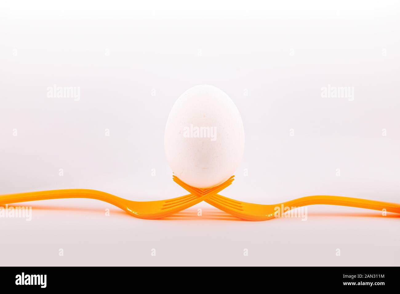 Zwei orange Gabeln Holding ein Ei. Konzept einschließenden Teamarbeit Stockfoto