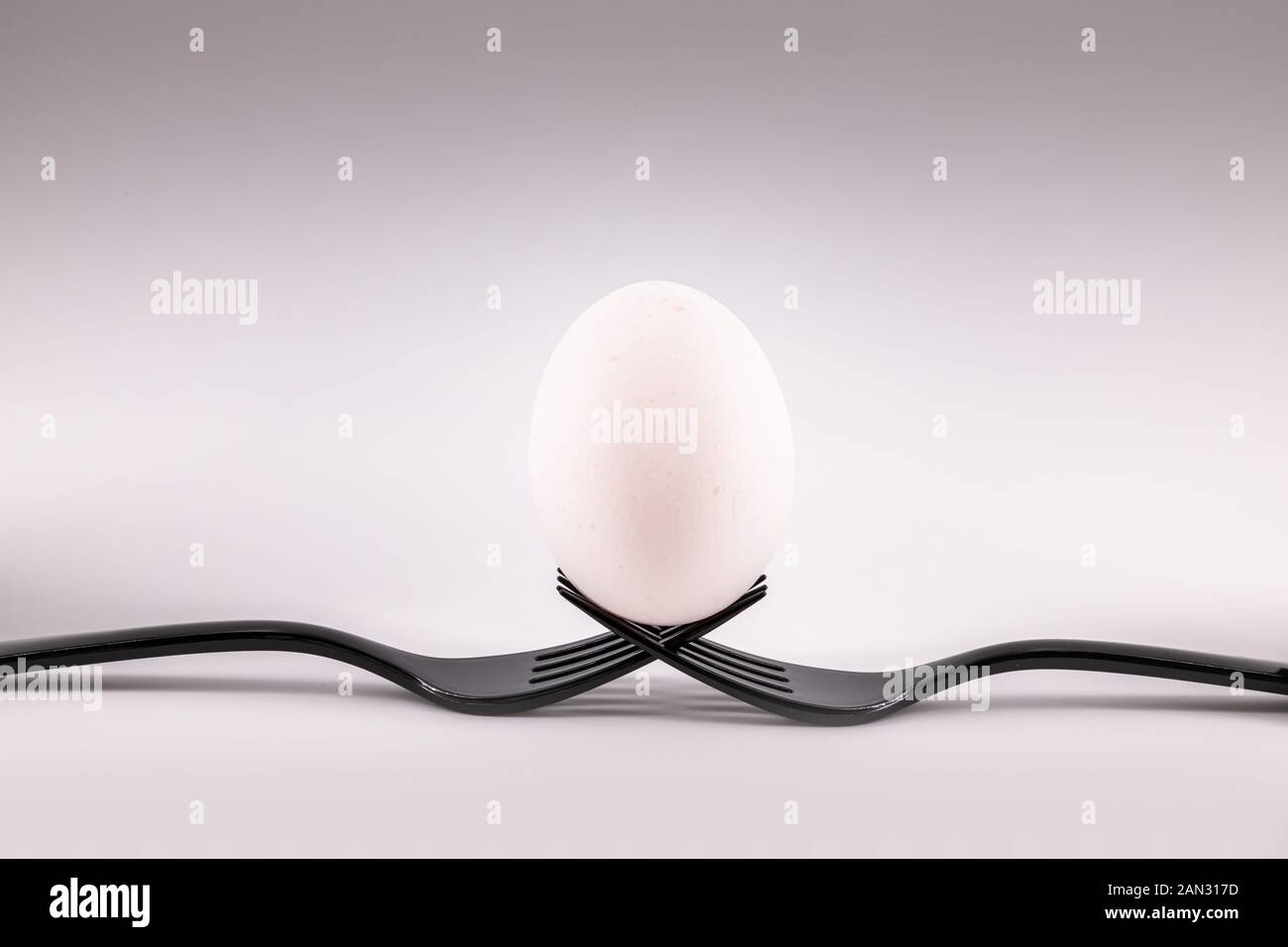 Zwei schwarze Gabeln Holding ein Ei. Konzept einschließenden Teamarbeit Stockfoto