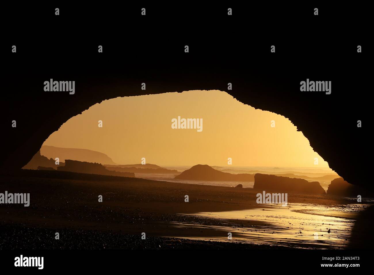 Natursteinbogen bei der Strandsonne von Legzira bei Sonnenuntergang mit schönen orangen Farben, Sidi Ifni, Marokko Stockfoto