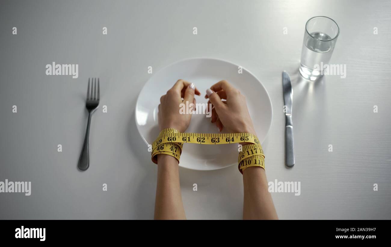 Hände mit tapeline auf leeren Teller gebunden, Mädchen mit kalorienzählen besessen Stockfoto