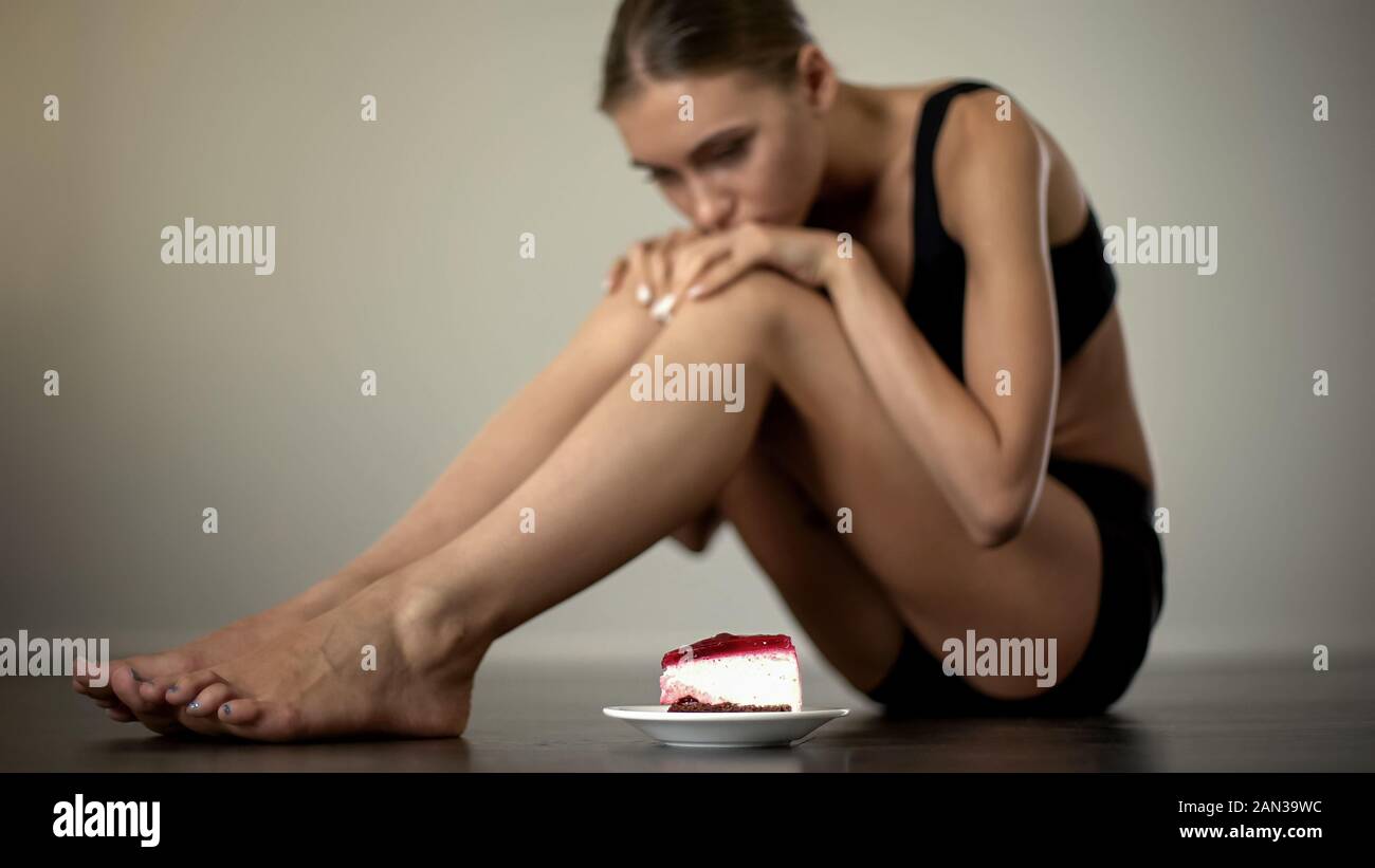 Schlanke Mädchen suchen, zögern am Kuchen zu essen, der Disziplinierung der Körper und Geist Stockfoto