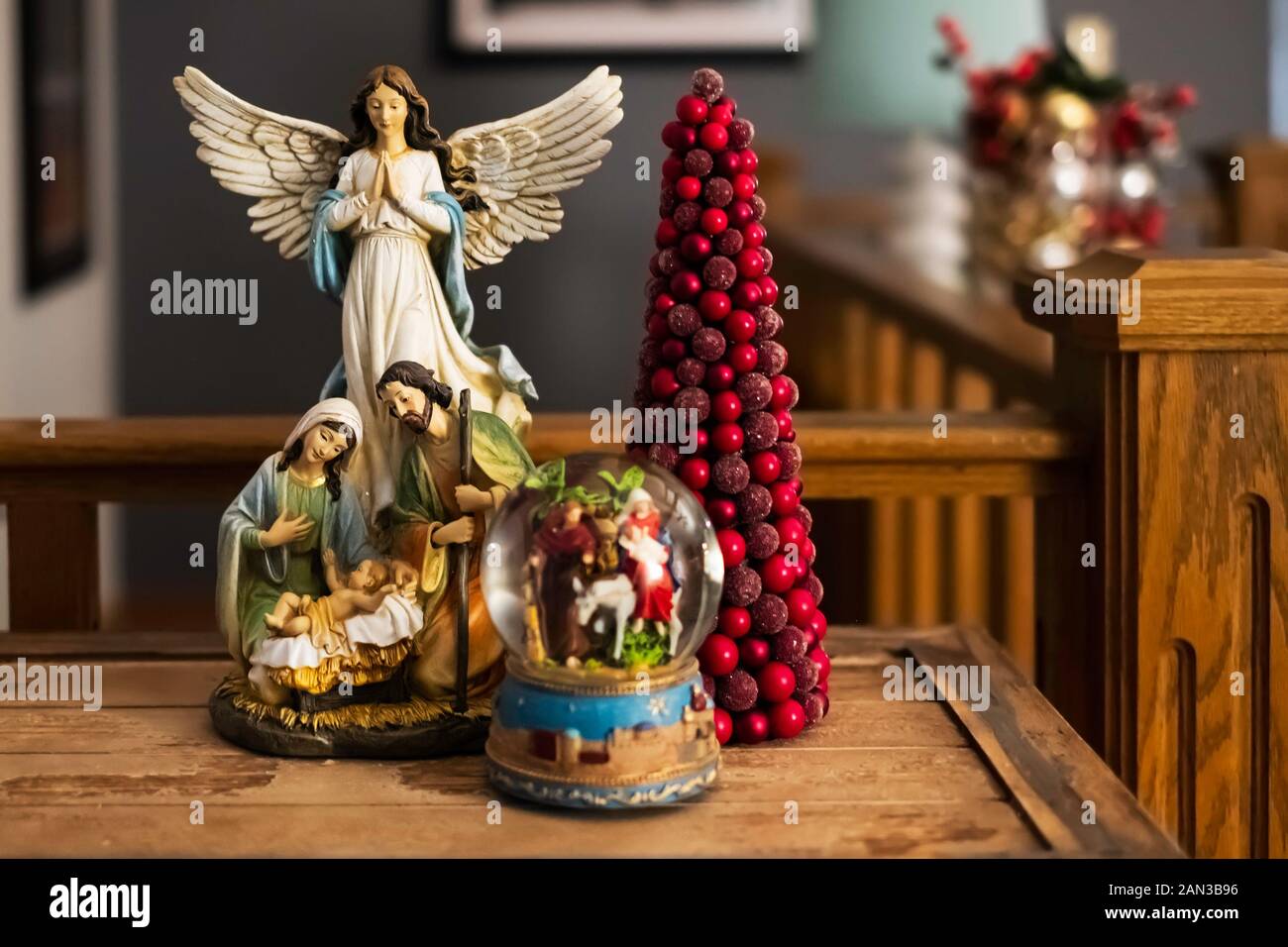 Weihnachtskrippe, Schneekugel und roter Weihnachtsbaum auf einem rustikalen Holztisch. Stockfoto