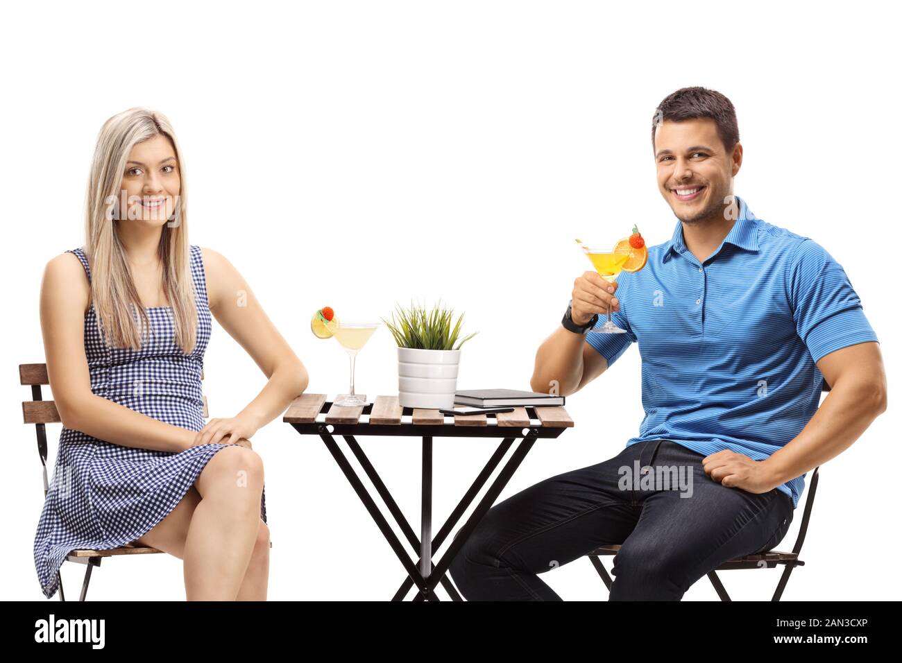 Ein Paar sitzt an einem Tisch mit Cocktails, die auf weißem Hintergrund isoliert sind Stockfoto