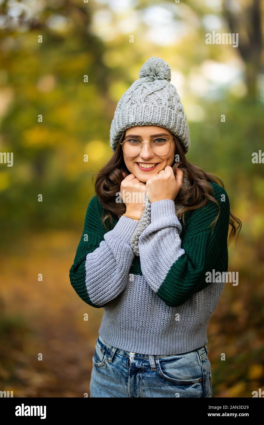 Junges Mädchen lacht im Freien in Hut und Schal graue Strickjacke Sonnenuntergang Sonne im Herbstpark Stockfoto