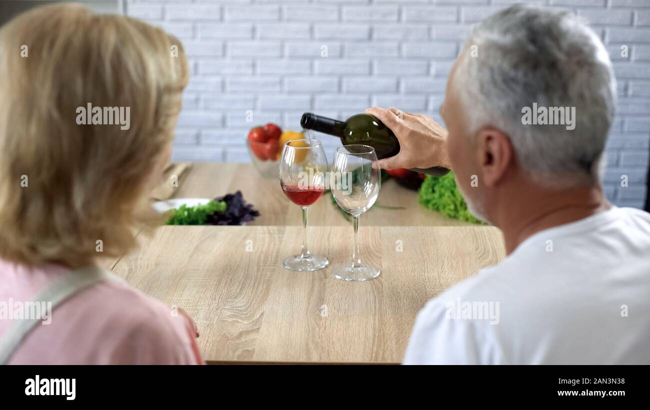 Pflege Mann gießen Rotwein in Gläser, romantische Tradition, alte Paar Liebe Stockfoto