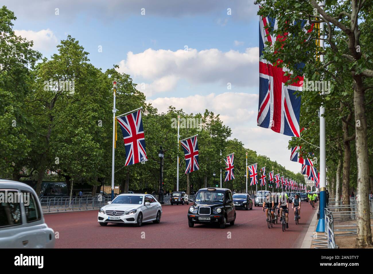 Die Flaggen von Union Jack fliegen im Frühjahr von Straßenpflaster in Der Mall, City of Westminster, London, Großbritannien mit grünen Bäumen und blauem Himmel Stockfoto