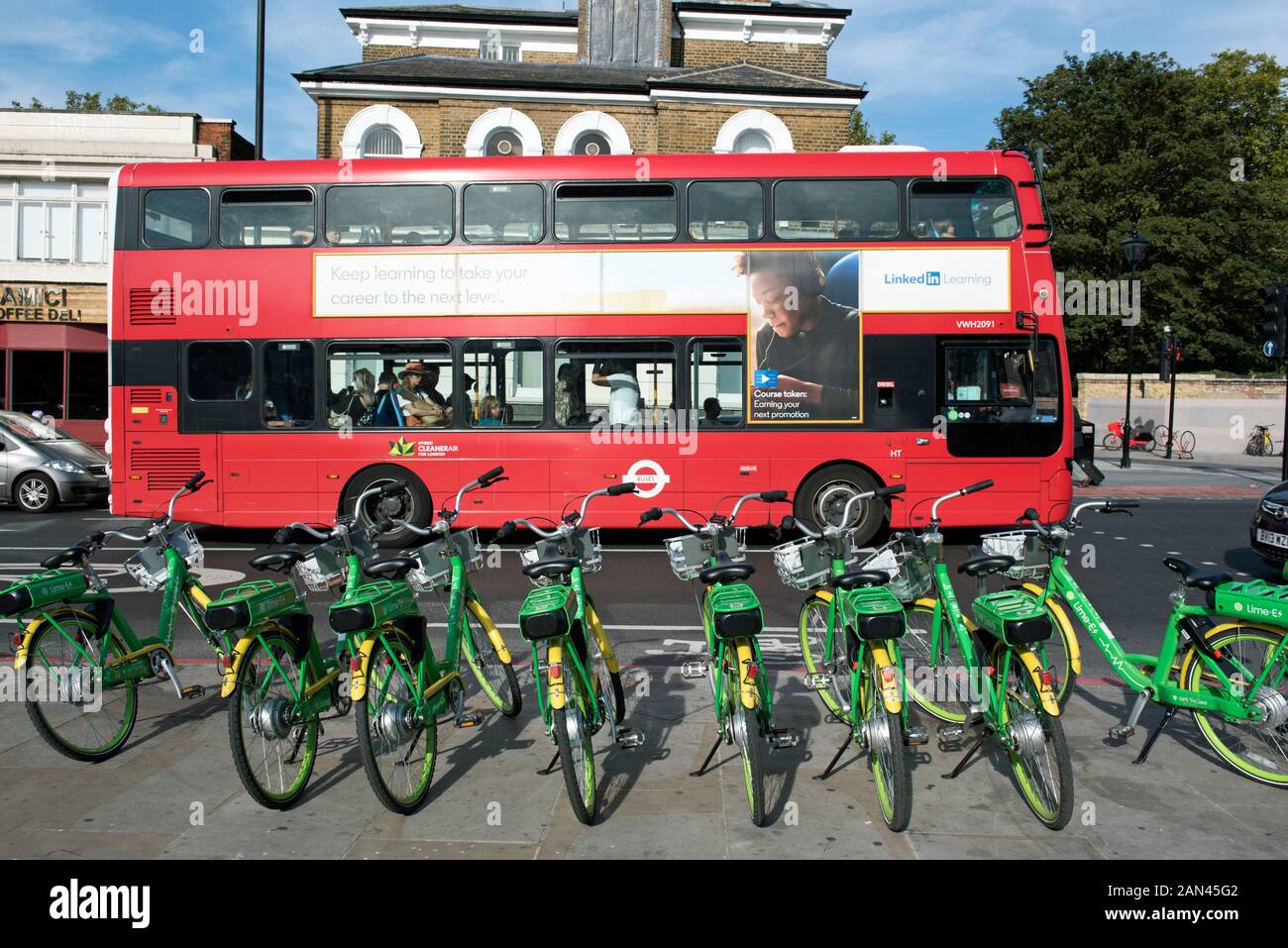 Lime E Elektrofahrräder auf dem Bürgersteig mit rotem Bus hinter der Holloway Road in Highbury Corner, Highbury, London Borough of Islington Stockfoto