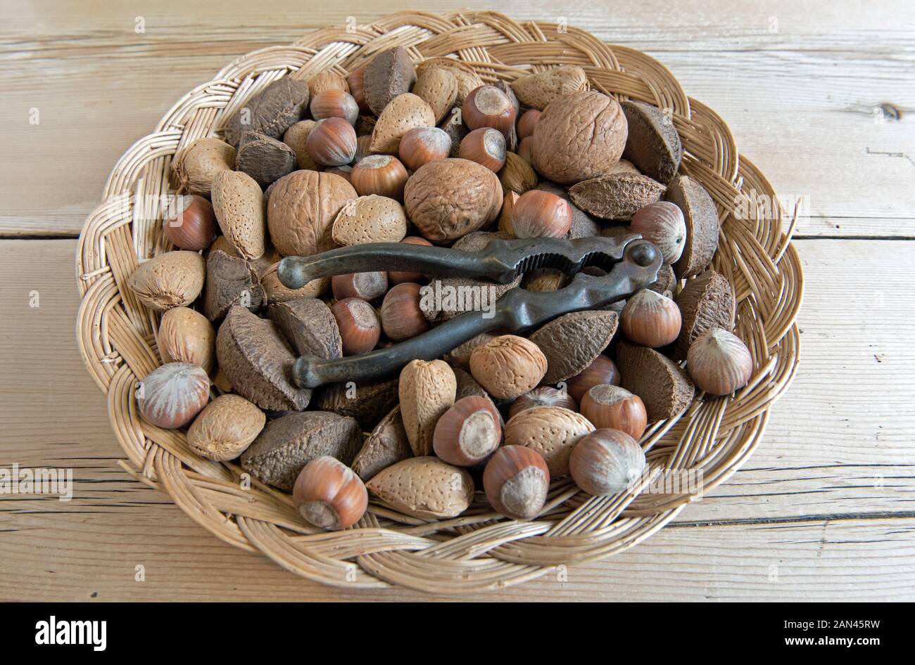 Gemischte Nüsse, Walnuss-, Brasilien- und Haselnüsse, in Korb mit Vintage-Nussknacker. Stockfoto
