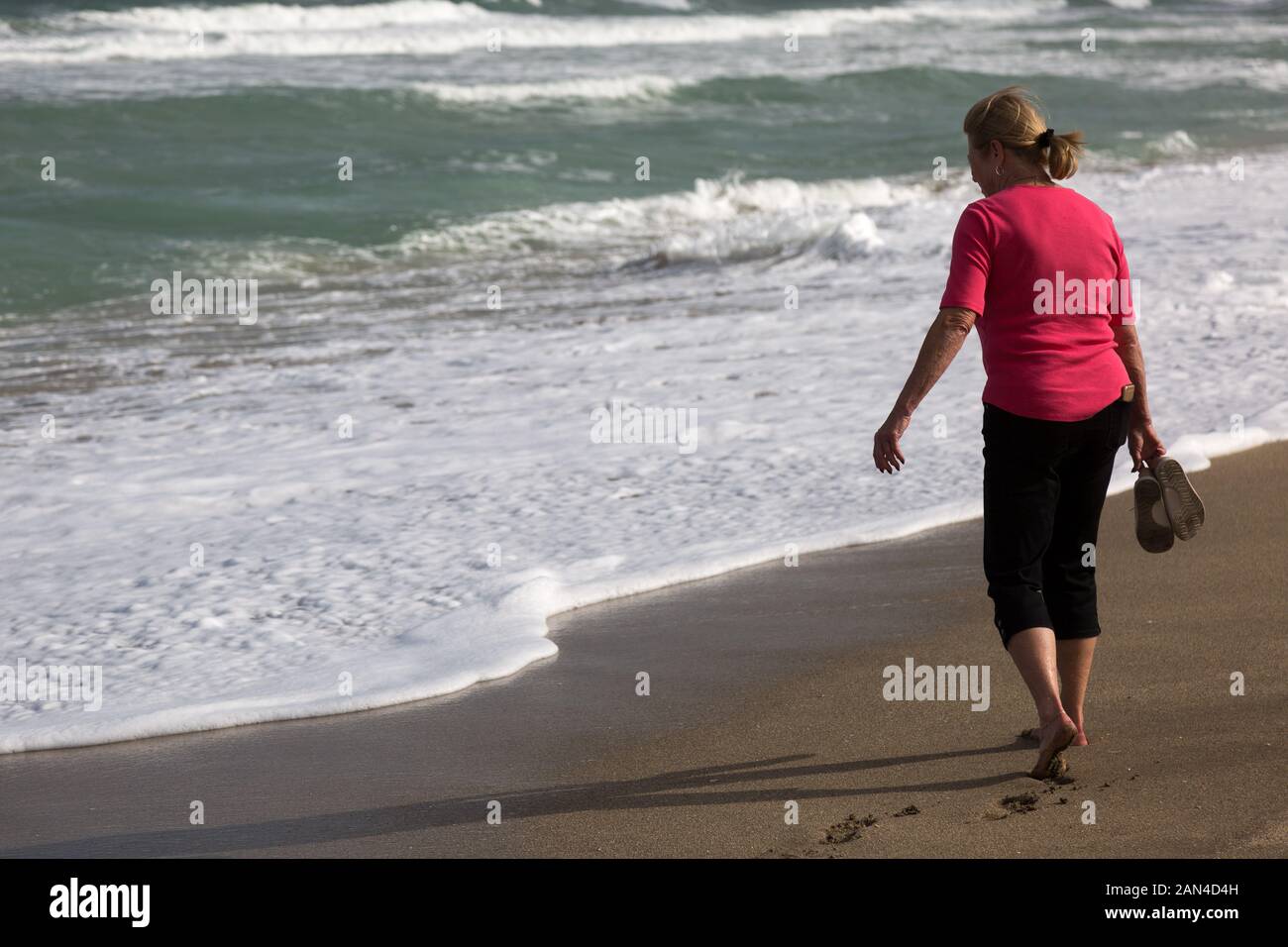 Eine barfuß Frau nähert sich das schaumige Surf auf dieser Hutchinson Island Beach in Stuart, Florida, USA. Stockfoto
