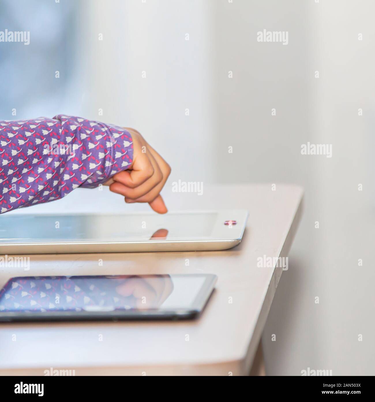 Schließen Sie die Seitenansicht der Hand ein kleines Mädchen mit und Tablet mit einem Privatsphäre Kamera abdecken, während der Tageszeit Stockfoto