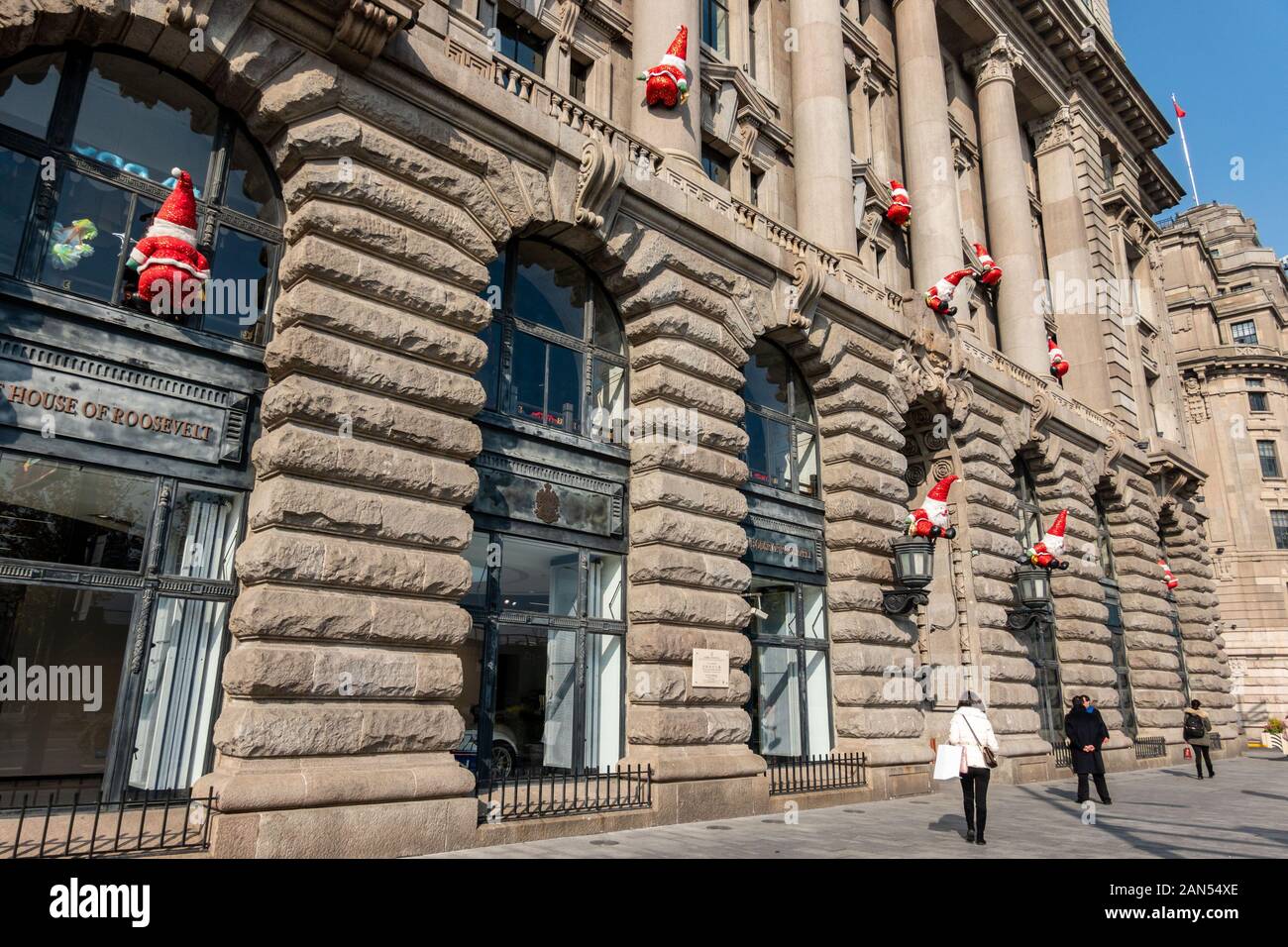 Menschen laufen unter dem Gebäude durch den Bund, die mit Santa Claus in Shanghai, China, 2. Dezember 2019 eingerichtet. 20 Santa Claus Zahlen wurden Stockfoto