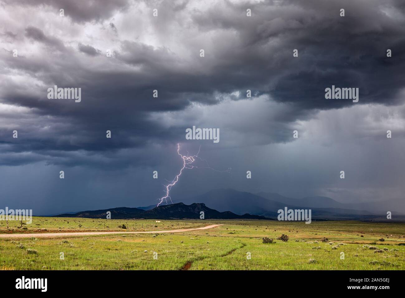 Ein Blitzschlag trifft auf einen Bergrücken, während sich ein Sommergewitter von der Front in der Nähe von Walsenburg, Colorado, bewegt Stockfoto