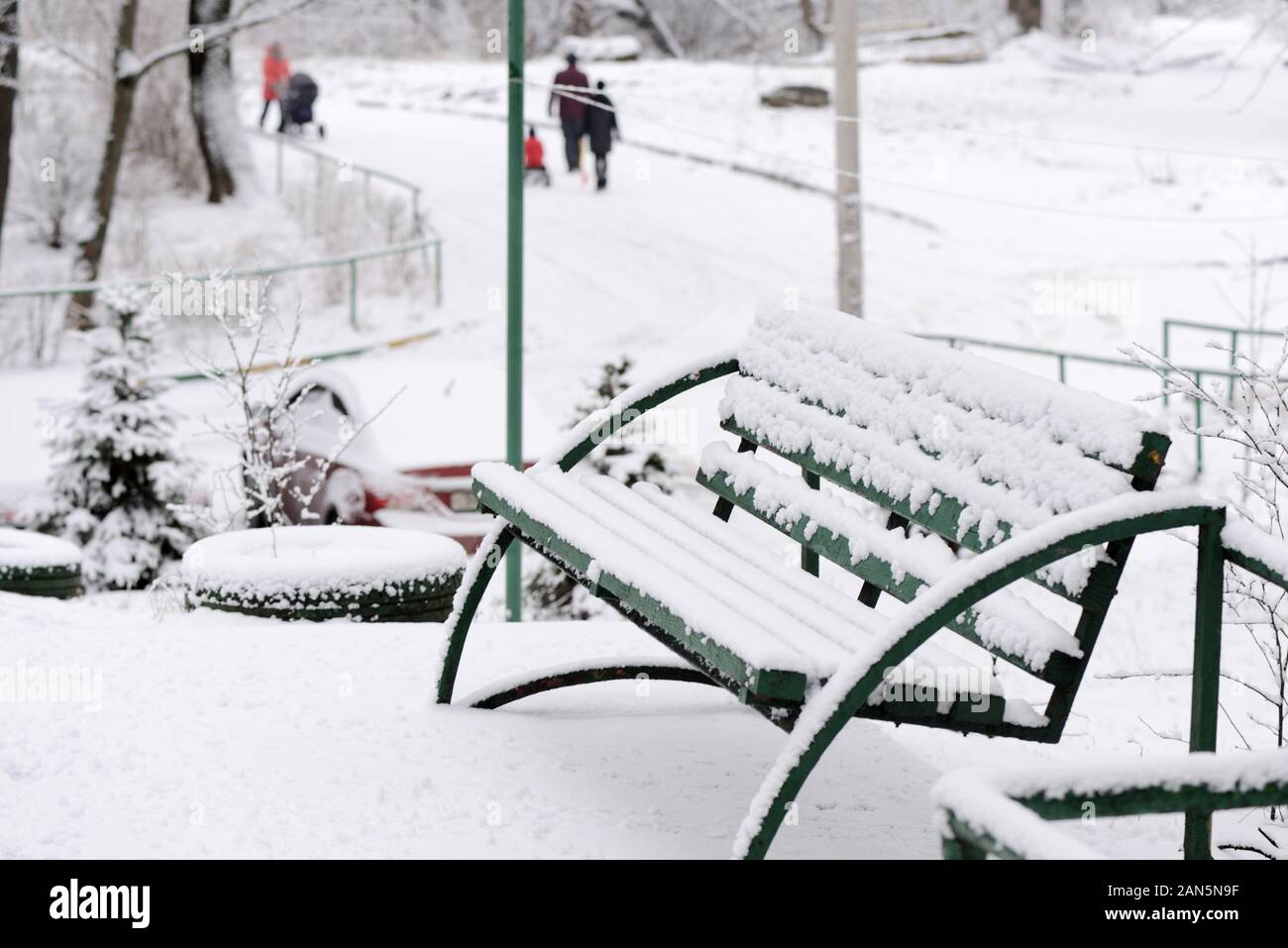 Grünen Holzbank mit Schnee an einem Ort Straße an einem Wintertag abgedeckt Stockfoto