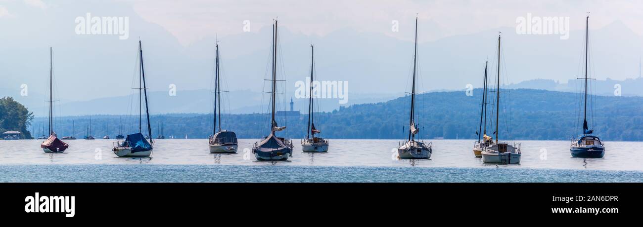 Panorama-Blick auf Segelboote, die am Ammersee ankern. Die Kirche im Hintergrund ist Marienmünster Dießen. Segeln ist eine beliebte Aktivität in der Nähe von Seen. Stockfoto