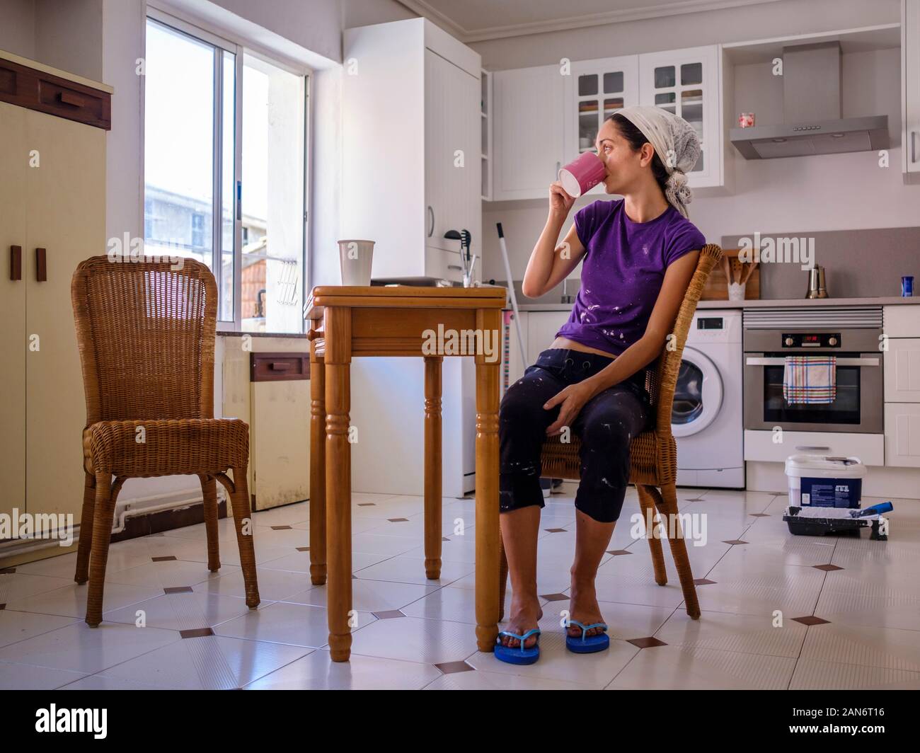 Frau mit einem heißen Getränk und ruhen auf einem Stuhl von der Lackierung für Ihr Zuhause Stockfoto