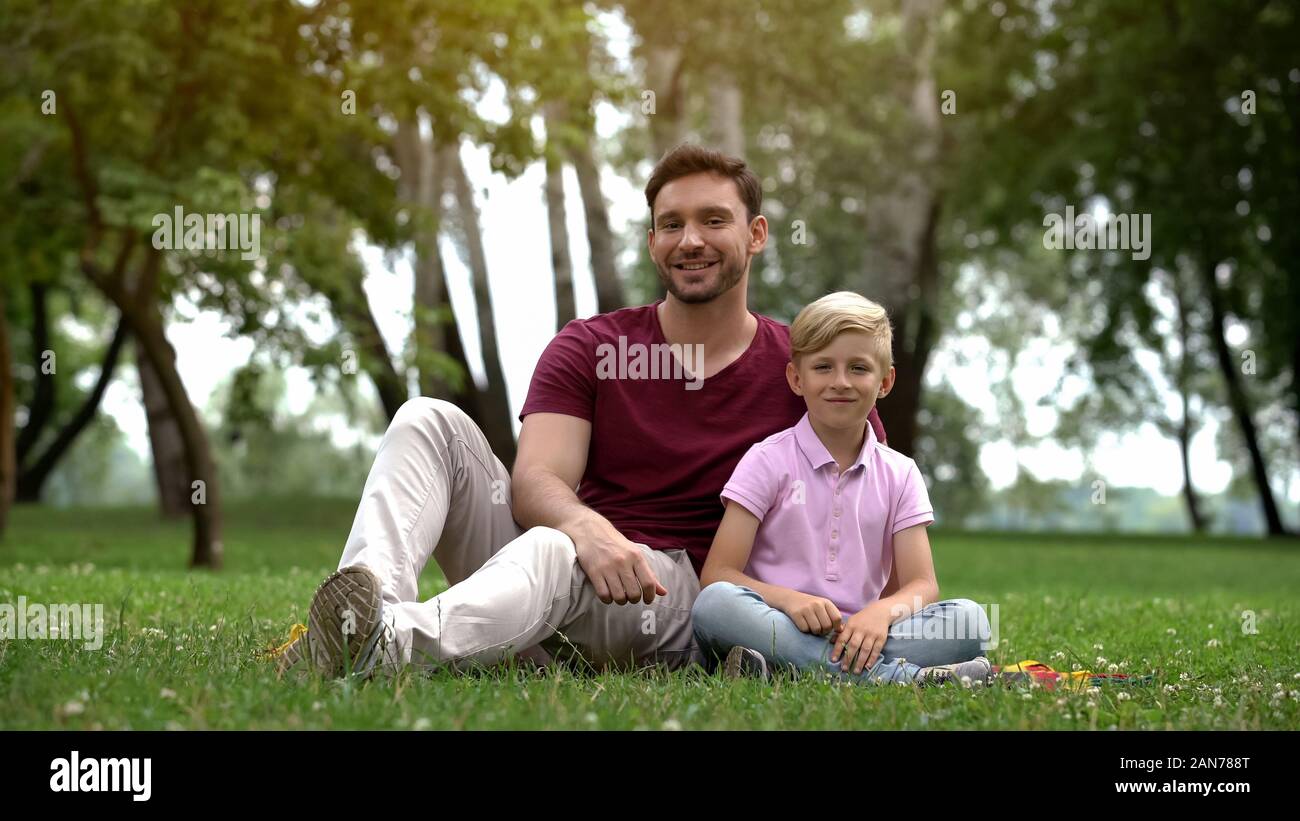 Gerne Vater und Sohn im Park sitzen, ad von sozialer Unterstützung für einzelne Väter Stockfoto