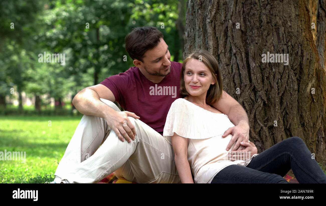 Glücklich schwanger Paar im Park sitzen, Planung gesichert Familienleben, Tierschutz Stockfoto