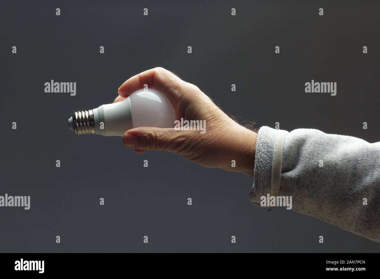 Tageslicht Energiesparbirne, in der Hand eines Erwachsenen; Lampe bereit, installiert und an das Stromnetz angeschlossen werden; es gibt Licht und wenig Wärme. Stockfoto