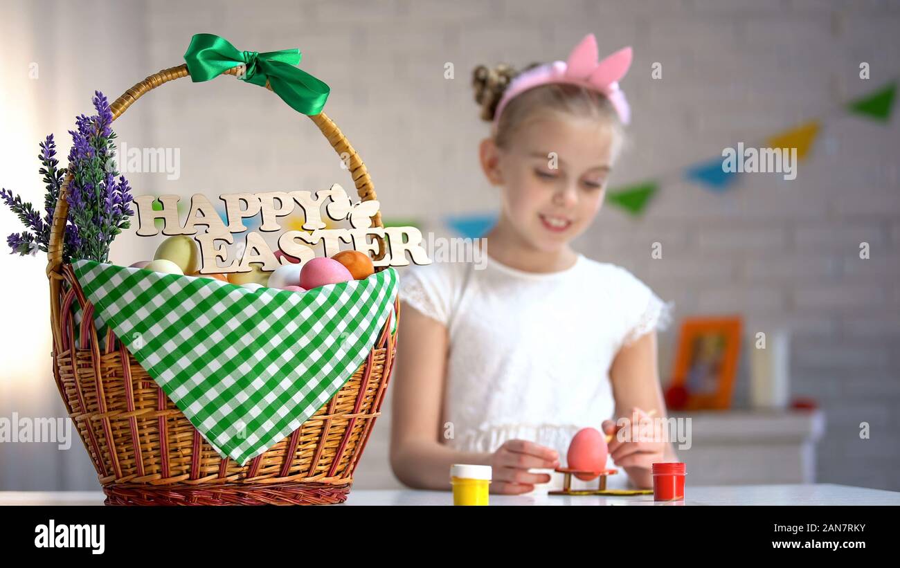 Frohe Ostern Anmelden Warenkorb, süße Mädchen malen Eier am Tisch sitzen, Urlaub Stockfoto