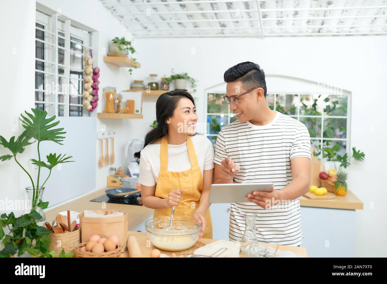Junge Familie zu Hause kochen, mit digitalen Tablet. Mockup für Rezept Stockfoto