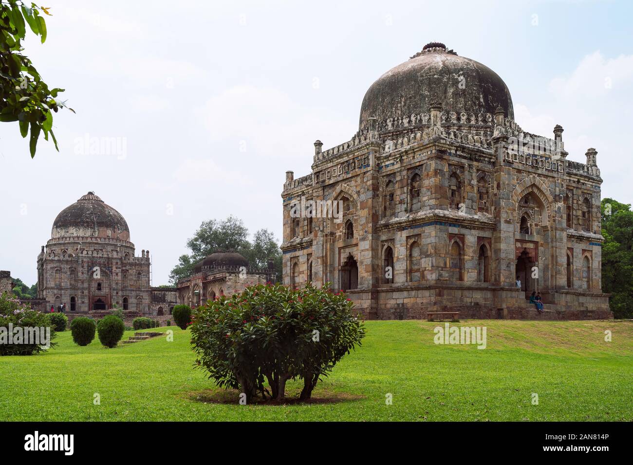 Bara Gumbad, oder große Kuppel, in Lodi Gärten an einem Sommermorgen von Bäumen und Rasenflächen unter blauen bewölkten Himmel, Delhi, Indien umgeben. Stockfoto