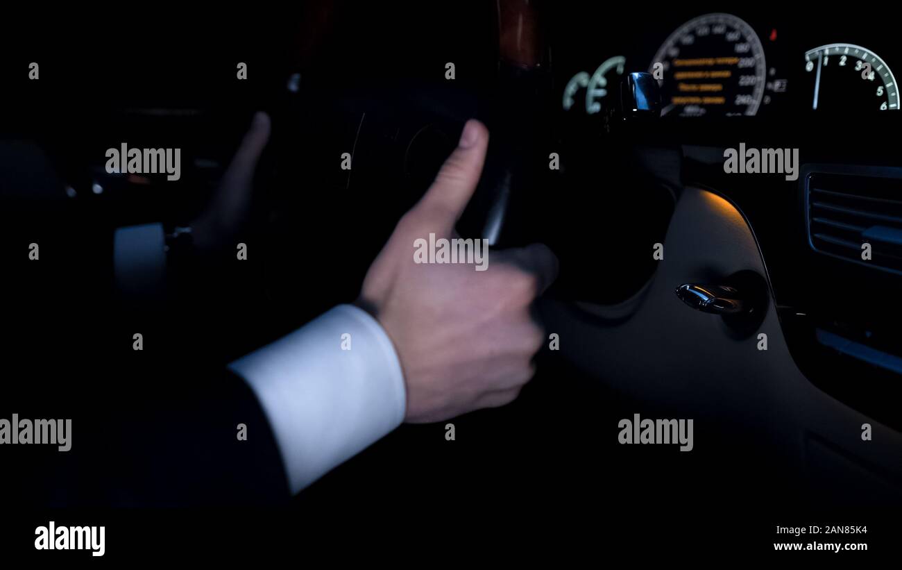 Mann, Auto, Hände auf Rad, Scheinwerfer am Auto Control Panel, Tachometer Stockfoto